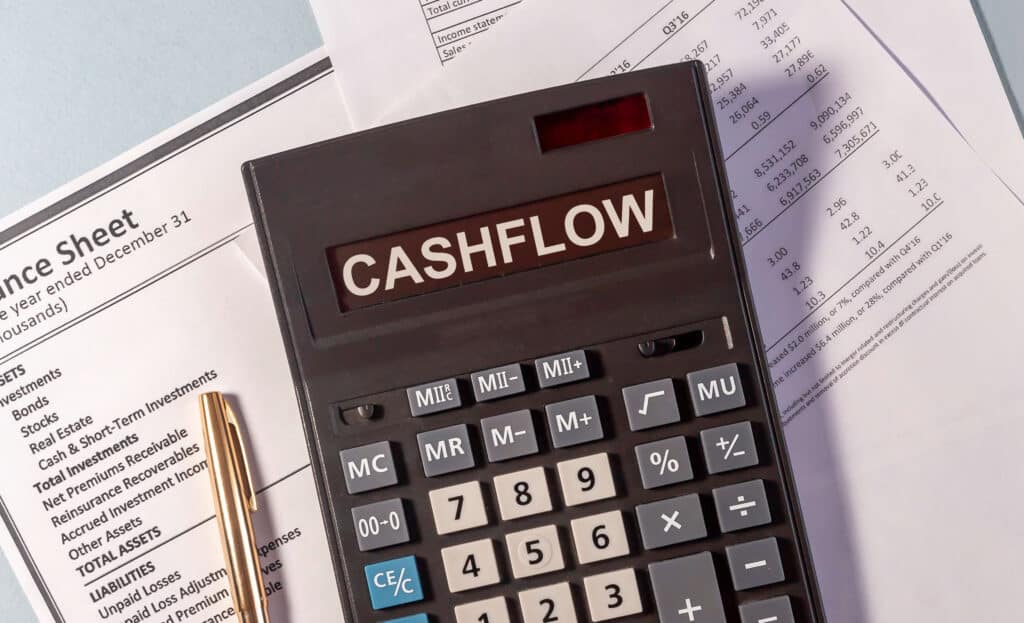 Calculator that reads "Cash Flow" sitting on top of balance sheets.