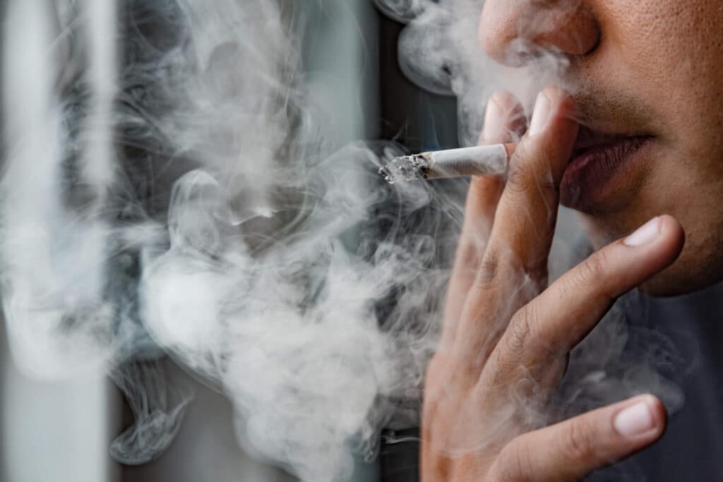 A cloud of cigarette smoke and a close-up of a smoker. 